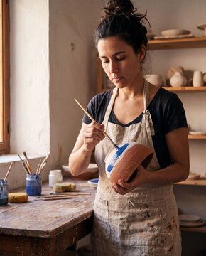 Potter Painting Ceramic Bowl in Studio. Handmade pottery craft