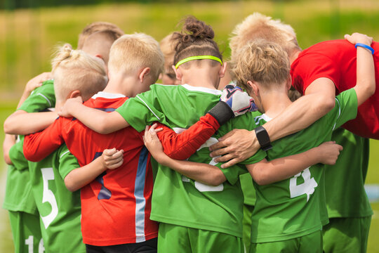 Youth Soccer Team in Green and Red Uniforms Gathering in Pre-Match Huddle with Coach - Children Football Team Unity and Motivation Concept
