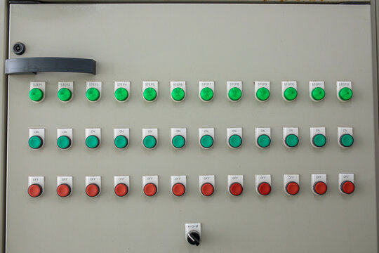 Industrial control panel features rows of green indicator lights with labeled push buttons and rotary switch. Electrical board displays numbered steps along with on and off power controls.