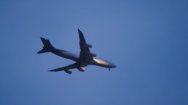 A large jet passenger plane is flying emergency landing through the twilight sky on a cloudy day. The sky is dark and cloudy