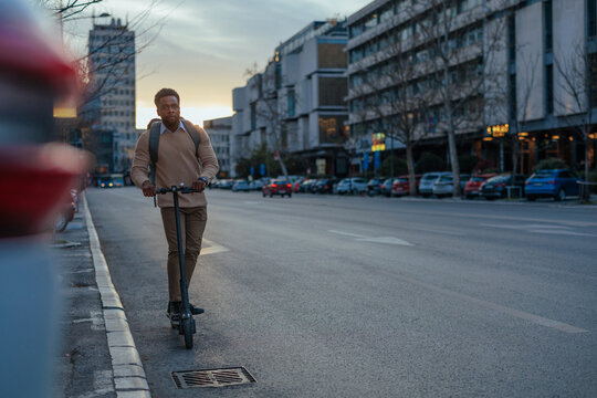 Young man riding electric scooter on city street