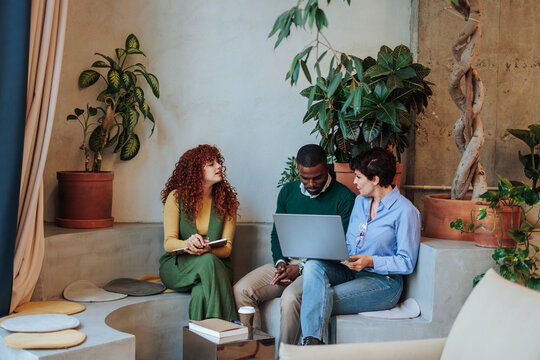 Diverse colleagues collaborating on laptop in modern office