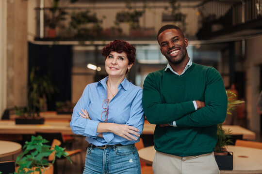 Diverse business partners smiling with arms crossed in office