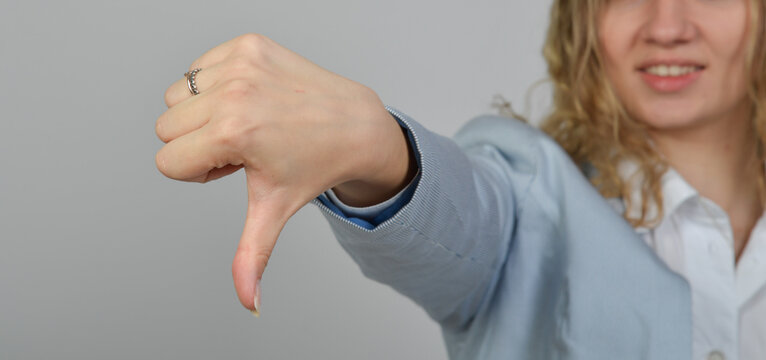 junge Frau zeigt mit ausgestreckter Hand einen Daumen nach unten. Ablehnung, Unzufriedenheit, Kritik, negatives Feedback, schlechte Bewertung und klare nonverbale Kommunikation.