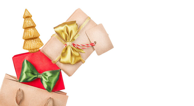 Collection of wrapped Christmas gifts, golden tree figurine, and shopping bag isolated on black