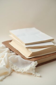 Una serena composici&oacute;n de naturaleza muerta que presenta papel superpuesto, un libro cerrado y una pieza de tela delicada