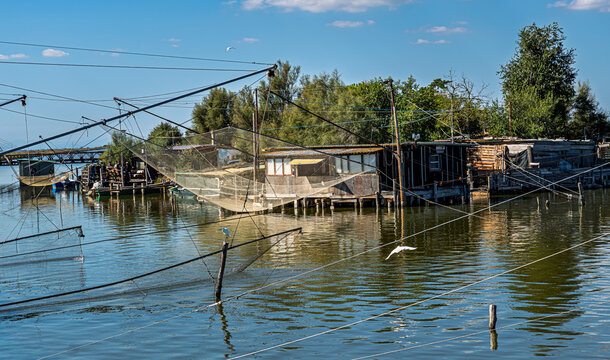 Im Brackwasser einer Lagune im Regionalpark Po-Delta stehen typische Fischerh&uuml;tten; die Netze sind zum Trocknen aufgeh&auml;ngt