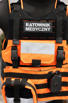 Paramedic tactical vest with pouches on orange emergency rescue plate carrier. Emergency medical technician chest rig displayed on rescue response uniform equipment.