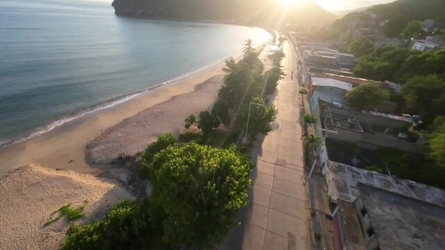 Aerial drone view gliding over Rio Caribe coastline, sandy beach, and green hills at sunrise