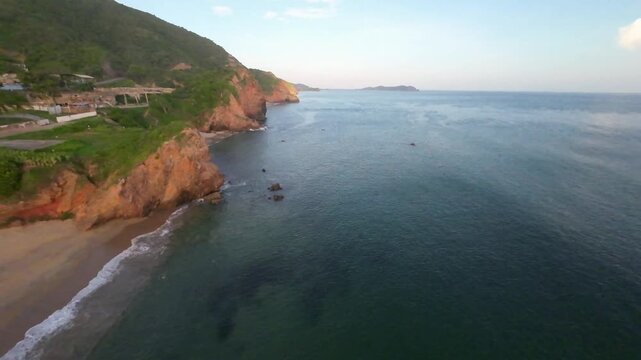 Aerial drone view gliding along Rio Caribe coastline with sandy beach and cliffs