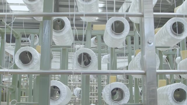 Industrial automation factory production line weaving plant of polypropylene yarn spools bags textile spinning synthetic fibers. White thread reels ropes making plastic sacks or fabric process