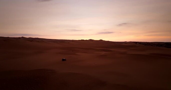 Aerial view of single off road buggy driving on vast desert sand dunes at sunset in Huacachina, Peru