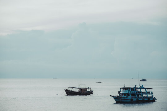 Fishing boats anchored on calm sea under cloudy sky