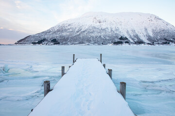 Snow covered pier on lake in serene winter - Tromso, Norway © muratart