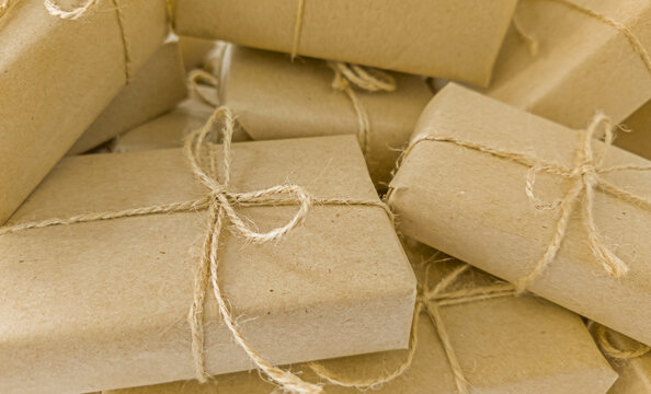 Close-up of multiple gift boxes wrapped in brown craft paper and tied with natural twine, filling the frame, concept of eco friendly packaging and zero waste holiday gift giving
