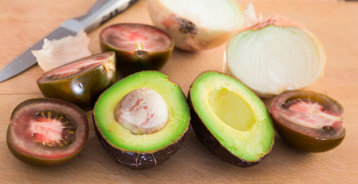 vegetables black tomatoes, avocado and onions on wooden board