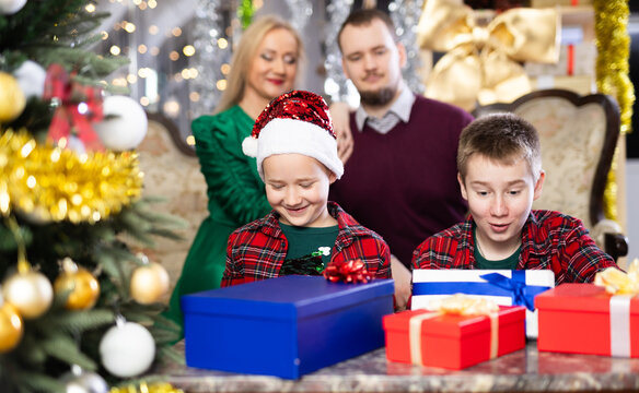 Children and parents give each other gift boxes during Christmas or New Year celebrations at home