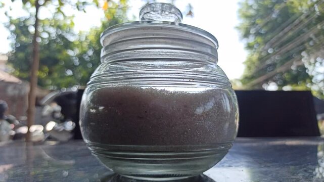 small round glass jar with an airtight sealed lid, commonly used as a container for storing sugar and other dry kitchen ingredients.