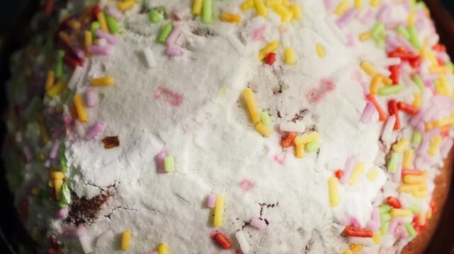 Close-up of traditional Easter bread topped with white icing and colorful sprinkles. Festive homemade pastry prepared for Easter celebration and holiday table. High quality 4k footage
