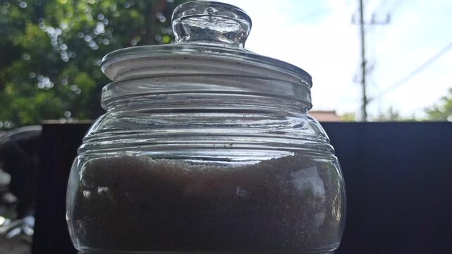 small round glass jar with an airtight sealed lid, commonly used as a container for storing sugar and other dry kitchen ingredients.