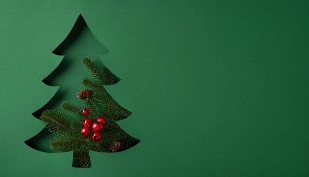 Creative Merry Christmas vision with cutout evergreen tree, red berries and festive New Year wishes on banner poster template
