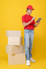 Delivery courier in red uniform using a tablet next to a stack of cardboard shipping boxes © Naypong Studio
