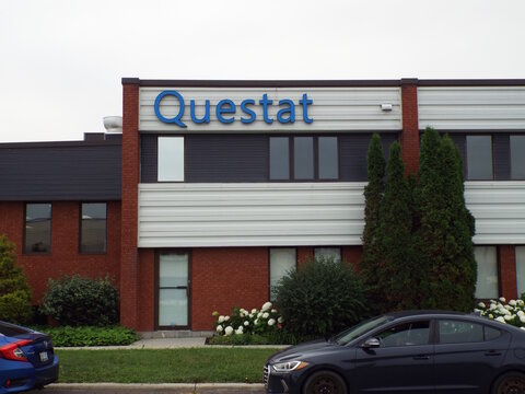 Gloucester, Ontario, Canada &ndash; July 31, 2026: A modern commercial building features a blue sign that reads "Questat" mounted above the entrance, with cars parked nearby at 5489 Canotek Rd.