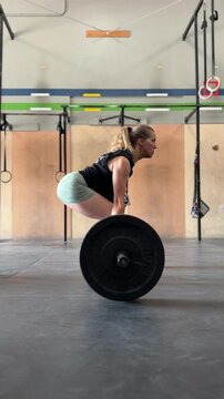 woman doing deadlifts with barbell and weights  in gym