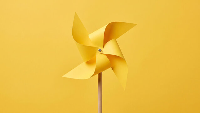 Yellow paper craft pinwheel windmill on a matching yellow background