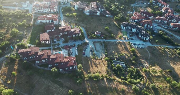 Establishing shot of hotel or residential area with houses and a few cars at sunset, sunrise, aerial shot