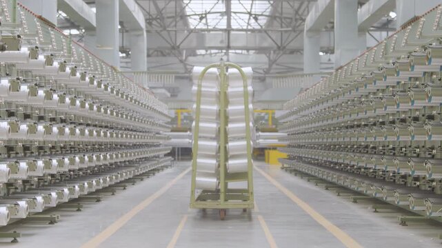 Worker working at industrial automation factory production line weaving plant polypropylene yarn spools bags textile spinning synthetic fibers. White thread reels ropes making plastic sacks or fabric