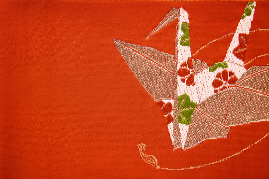 Embroidered paper cranes on vermilion kimono fabric with copy space