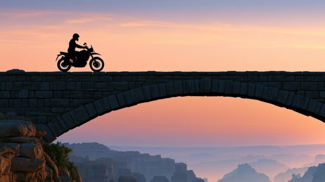 Rider on motorcycle silhouetted crossing a stone bridge at sunset