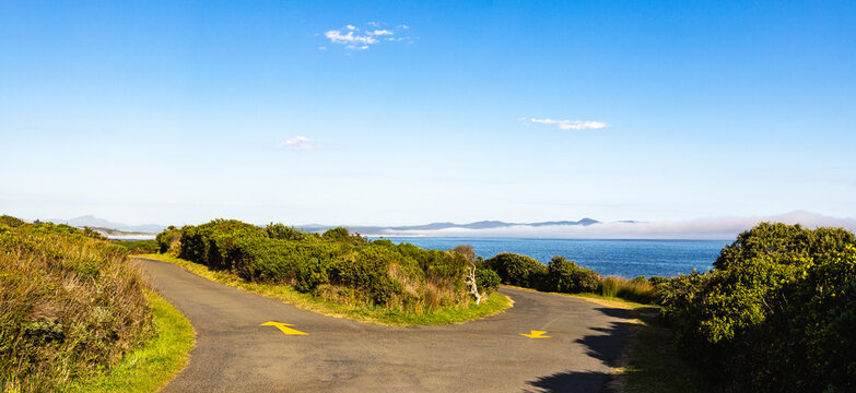 yellow arrows, winding asphalt road above the beautiful cliff path with views to Walker Bay, Hermanus, South Africa
