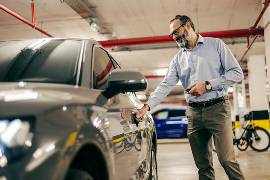 Mature man opening car door in underground parking