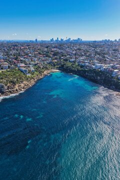 Aerial view of Gordons Bay with its turquoise waters, rocky coastline, and the Sydney skyline in the background, Coogee, New South Wales, Australia.