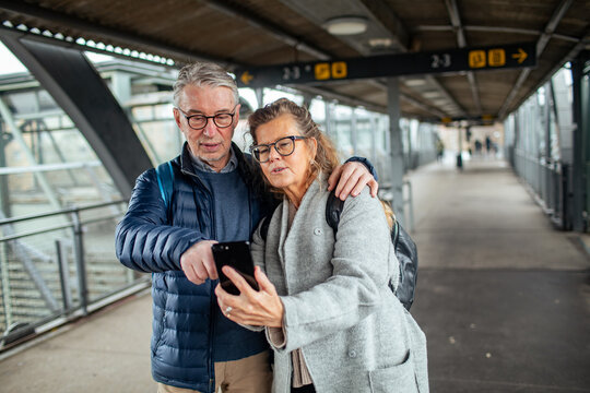 Senior couple checking directions on smartphone at train station