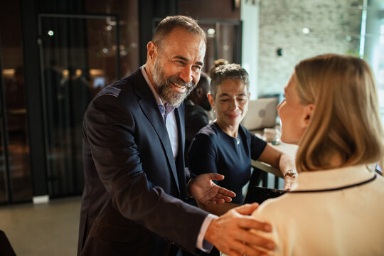 Smiling executive welcoming colleague with a friendly shoulder pat