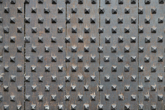Closeup of medieval style studded wooden door spikes texture in Europe