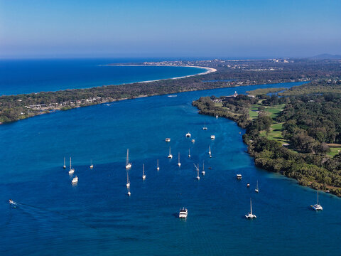Aerial view of Cook Island surrounded by turquoise waters with numerous boats anchored in the bay, lush green vegetation, and a sandy coastline in New South Wales, Australia.