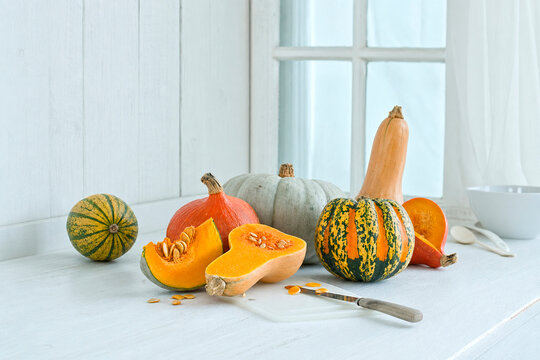 Various pumpkins and butternut squash on a rustic white kitchen