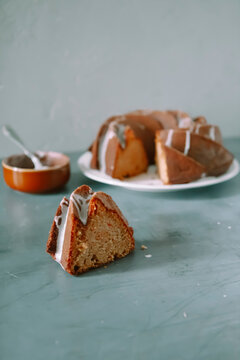 Glazed carrot cake slice with icing and whole bundt cake on plate
