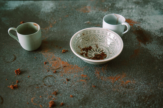 Empty dessert bowl with coffee cups and crumbs on table