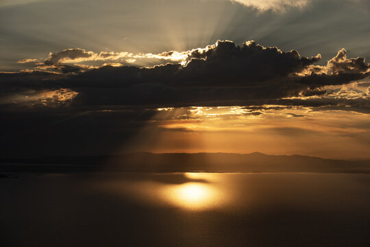Aerial view of Great Salt Lake at sunset with golden light reflecting on the water surface and dramatic clouds in the sky, Salt Lake City, Utah, United States.