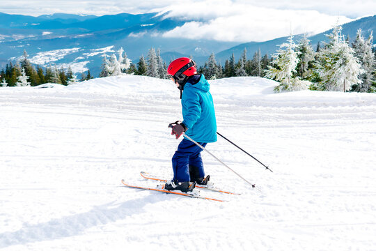 Active kid boy riding downhill,learn skiing in mountains alpine winter resort.little child enjoy extreme sport activities recreation,family luxury vacation