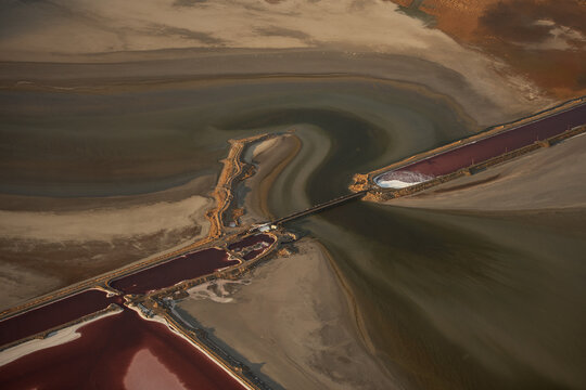 Aerial view of the Great Salt Lake showing distinct pink and green saline water separated by a causeway, with surrounding salt flats in Salt Lake City, Utah, United States.