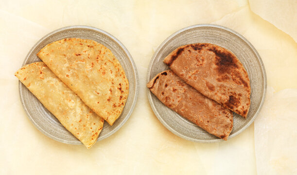 Folded Indian flatbreads placed on circular plates from overhead view
