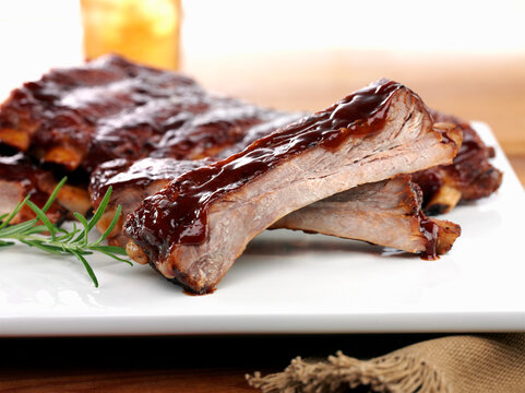 BBQ baby back ribs glazed with barbecue sauce on a white plate