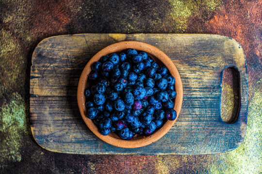Bowl of raw organic blueberries on wooden board