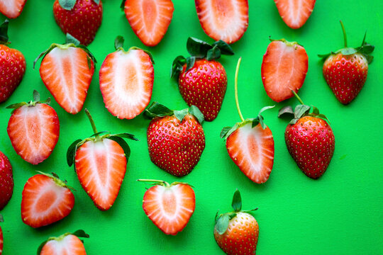 Fresh whole and halved Strawberries on green background